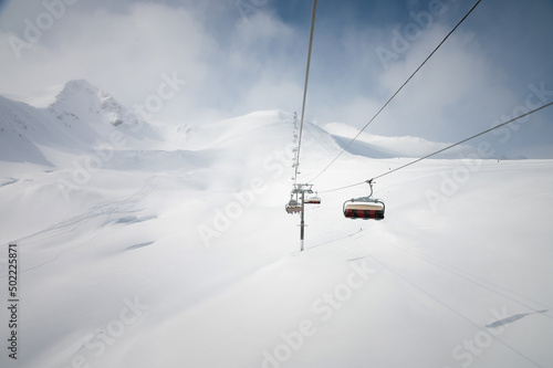 Chairlift in a ski resort, view from the funicular to the mountains and snow-covered fields for freeride skiing