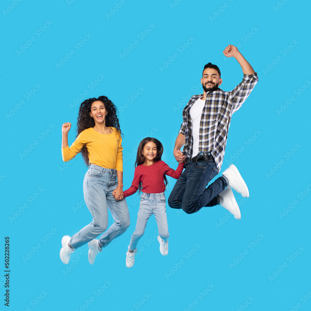 Cheerful Middle Eastern Family Of Three Jumping Over Blue Background Cheerful Middle Eastern Family Of Three Jumping Over Blue Background
