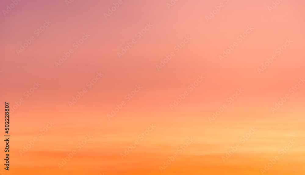 Sunset sky with orange, yellow, pink and purple sunlight in the evening on romantic golden hour clouds background