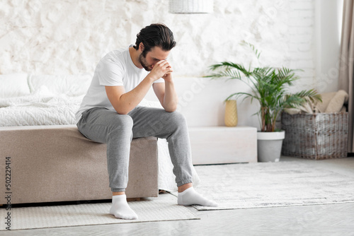 Photos Lonely young man sitting on bed alone, copy space