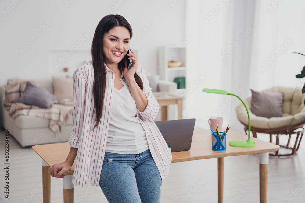 Portrait of attractive cheerful confident long-haired woman manager talking on phone working remotely at home indoors Portrait of attractive cheerful confident long-haired woman manager talking on phone working remotely at home indoors