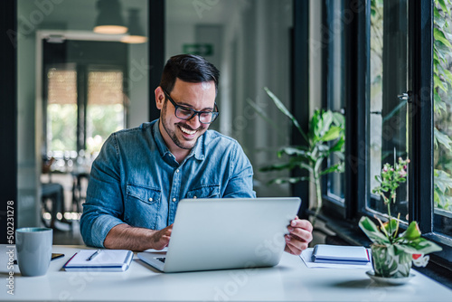 Smiling businessman analyzing success plan on laptop while working at home