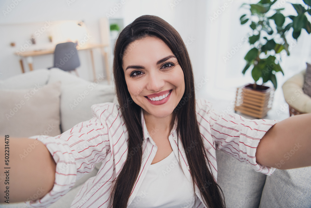 Self-portrait of attractive cheerful long-haired woman sitting on divan resting spending day life at home indoors Self-portrait of attractive cheerful long-haired woman sitting on divan resting spending day life at home indoors