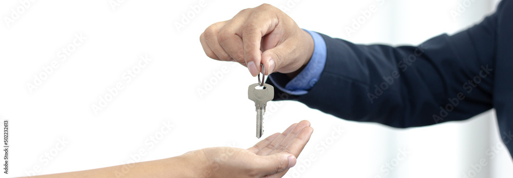 Sales manager or real estate agent holds the key handing it to the customer after signing the house purchase contract with home insurance, Trading of mortgages and insurance concept. Sales manager or real estate agent holds the key handing it to the customer after signing the house purchase contract with home insurance, Trading of mortgages and insurance concept.