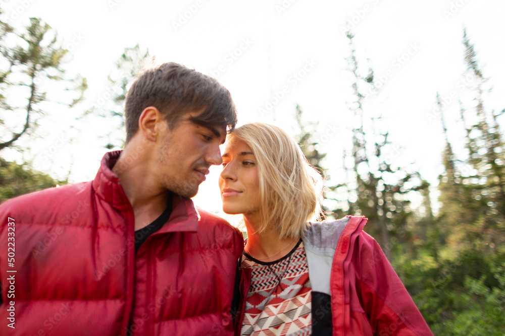 Fototapeta premium Beautiful young woman and man walk, hug and kiss in mountain nature at sunse