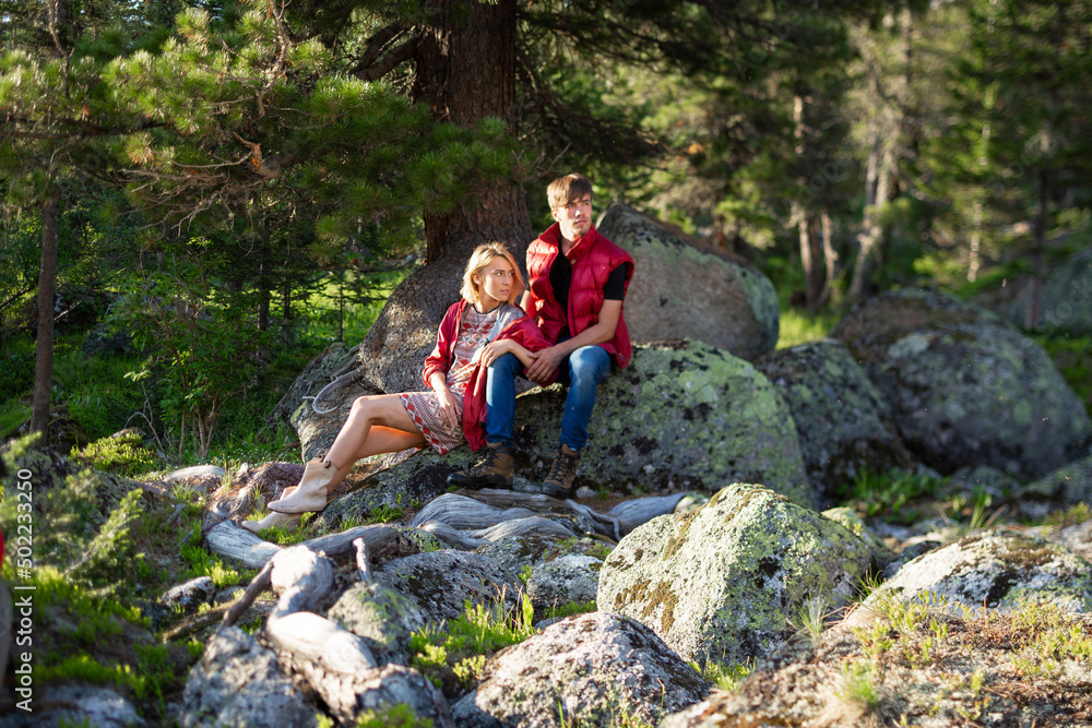 Naklejka premium Beautiful young woman and man walk, hug and kiss in mountain nature at sunse