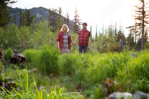Beautiful young woman and man walk, hug and kiss in mountain nature at sunse with tilt-shift effect