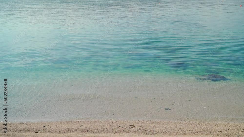 Video of the coastline of the sea and the beach with a calm small wave on a summer sunny day