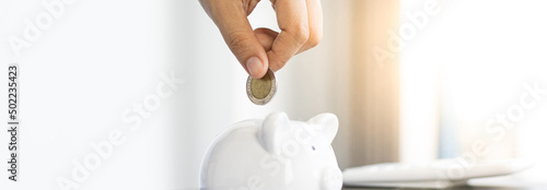 Businessman's hand holds the money in the piggy bank for saving money for future use, saving money for finance accounting concept.