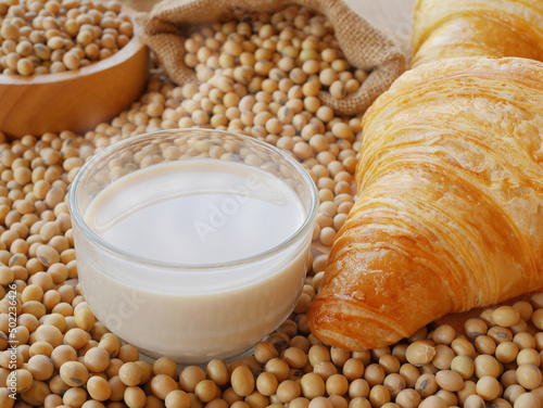 Delicious soy milk on lots of soy beans with sack of soy beans and some croissant and wooden bowl of soy beans