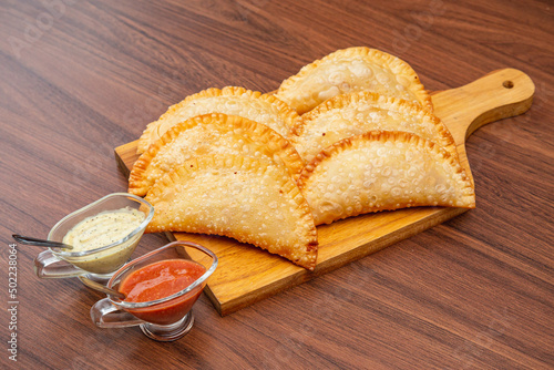 fried pastry, fogazza, meat pastry, cheese pastry, served with mayonnaise and chili sauce, timico Brazilian bar snack. photo