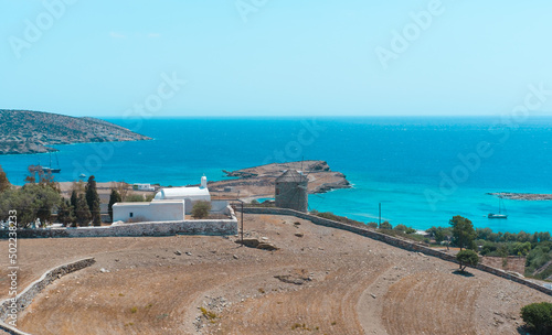 old stone wind mill on Greek Islands, small church or chapel, hill over the sea coast, seascape horizon, Schinoussa Chora view photo