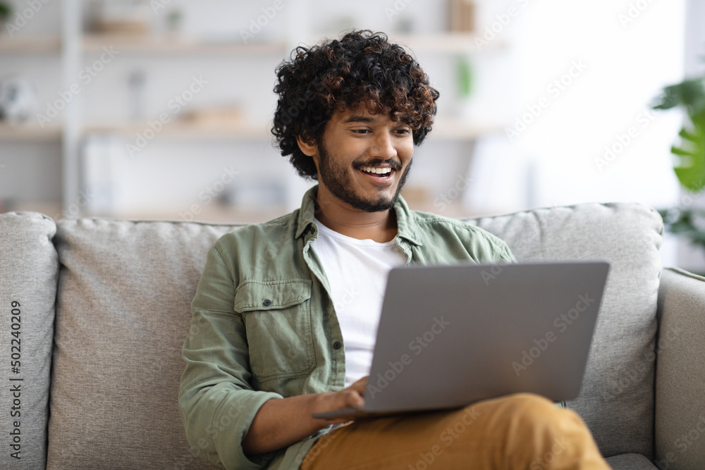 relaxed dark-skinned guy using notebook at home relaxed dark-skinned guy using notebook at home