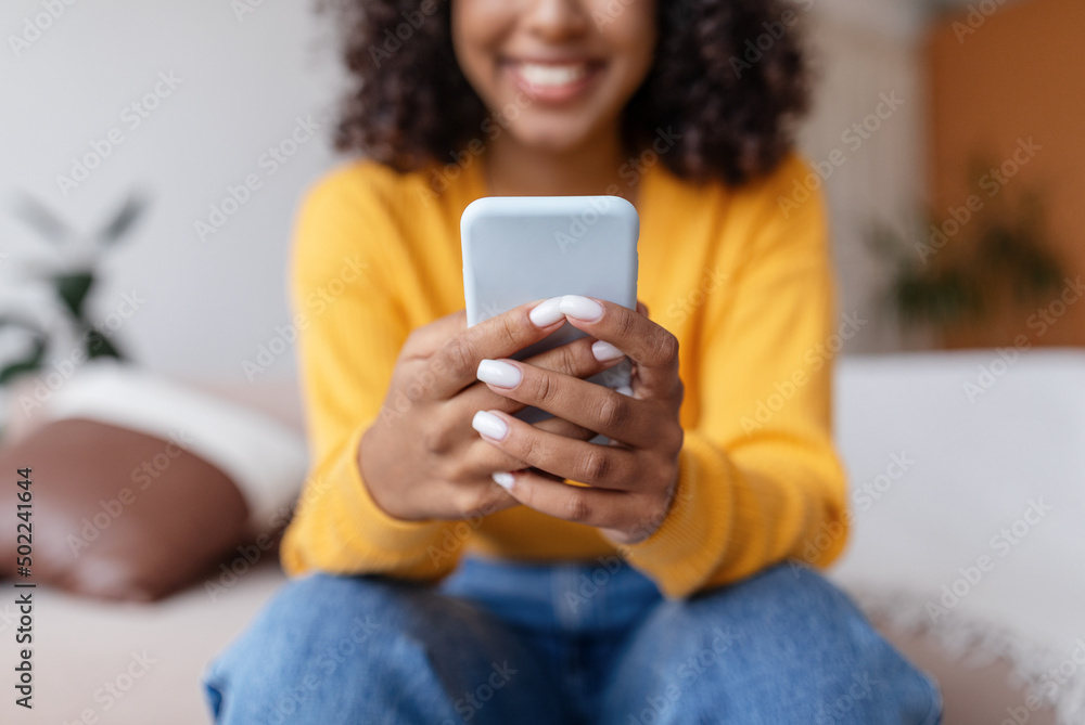 Unrecognizable young black woman using mobile phone, having online video call, communicating in social network at home Unrecognizable young black woman using mobile phone, having online video call, communicating in social network at home