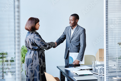 Portrait of African American business advisor shaking hands with female client after meeting in office