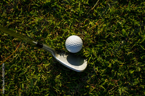 Golf clubs and balls on a green lawn in a beautiful golf course with morning sunshine. golf ball on green grass ready to hit on golf course background.