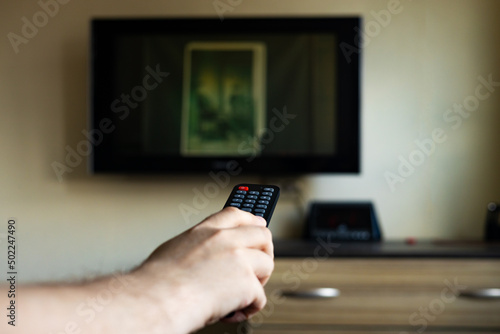 The TV infrared remote control switches channels to TV in your hands. Close-up, selective focus.