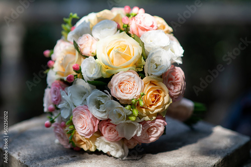 a wedding bouquet of roses lies on a concrete slab in nature