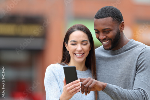 Happy interracial couple consulting phone text