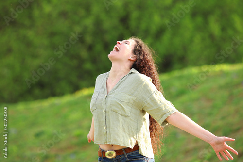 Photography Happy woman screaming in a park outstretching arms