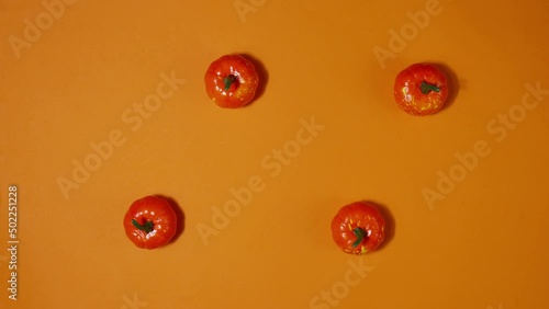 Stop motion animation of halloween mini pumpkins on orange background. Trick or Treat. Top view