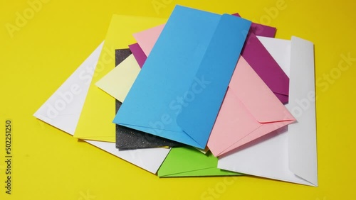 Stop motion animation stack of colored envelopes on a yellow background