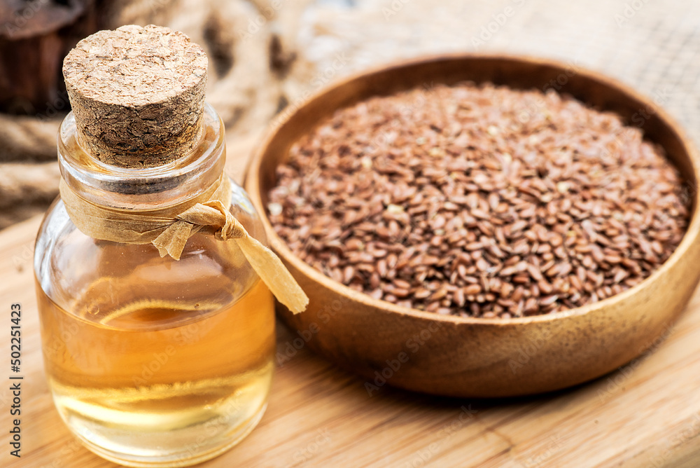 linseed oil in a glass bottle close-up and linseeds in a wooden bowl. linseed oil in a glass bottle close-up and linseeds in a wooden bowl.