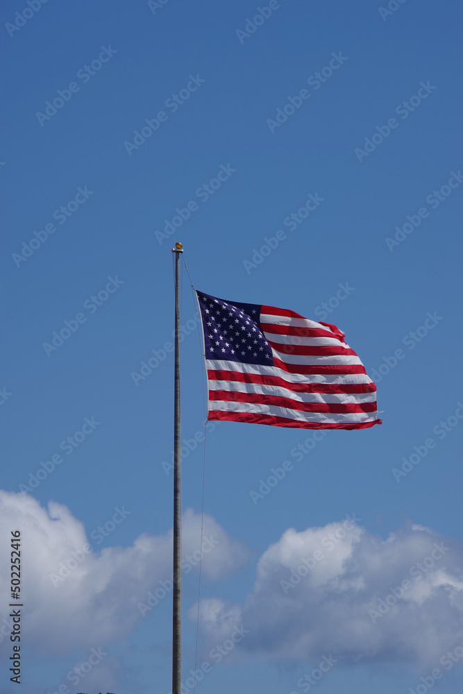 The United States flag waving high in the blue sky