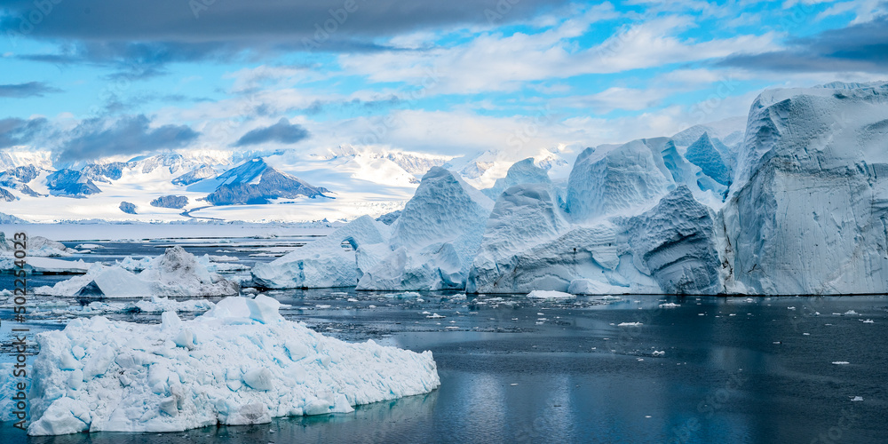 Tabular Iceberg in front of Antarctic Peninsula pictured inside Larsen A inlet with a very scenic cloudy sky and mountains at the backgound