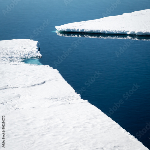 two Icefloats pictured inside Larsen A inlet with blue sky and calm seas photo