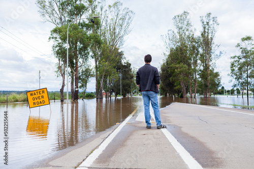 Person looking at floodwaters over road cutting off access via New England Highway through singleton photo