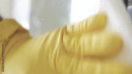 Blurred Shooting with a Man Wearing Gloves Cleaning the Cooking Stove with Spray Detergent, a Routine Activity in Kitchen Chores.