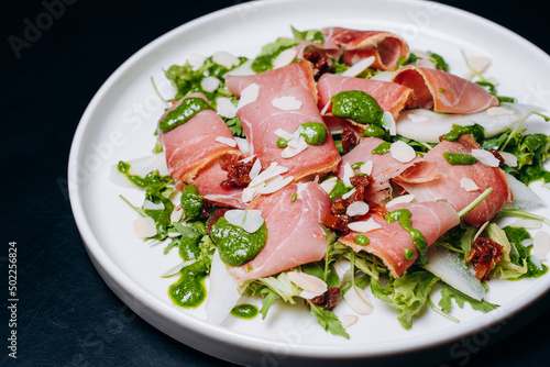 salad with prosciutto and avocado with avocado sauce on a white plate