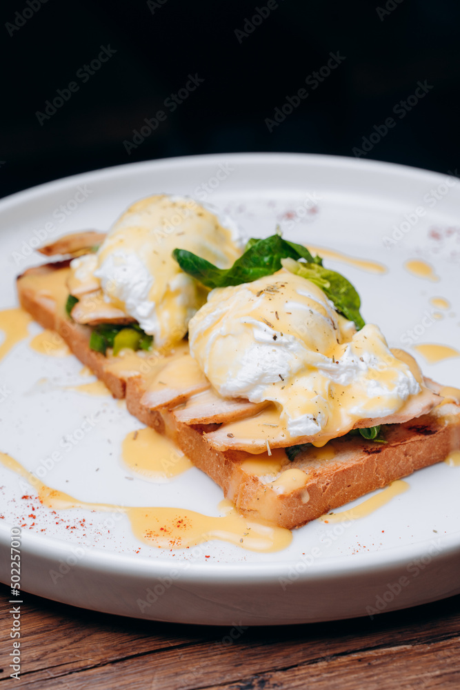Toast with egg poached, healthy breakfast of waffles, poached egg with bacon and arugula. Brioche sandwich Toast with egg poached, healthy breakfast of waffles, poached egg with bacon and arugula. Brioche sandwich