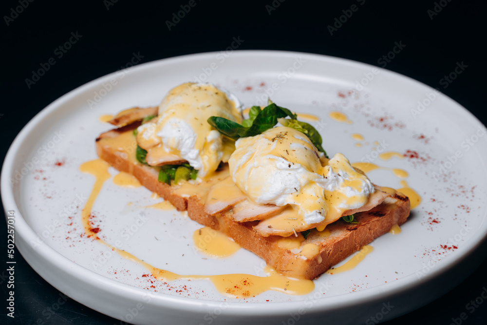 Toast with egg poached, healthy breakfast of waffles, poached egg with bacon and arugula. Brioche sandwich Toast with egg poached, healthy breakfast of waffles, poached egg with bacon and arugula. Brioche sandwich