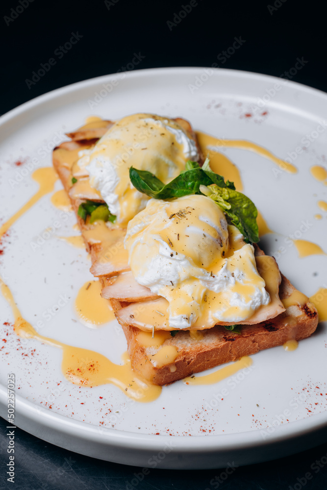 Toast with egg poached, healthy breakfast of waffles, poached egg with bacon and arugula. Brioche sandwich