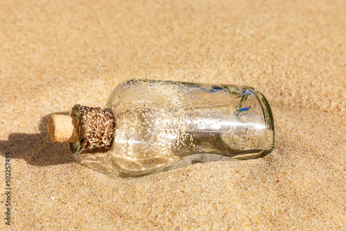 Flaschenpost im Sand an einem Strand.