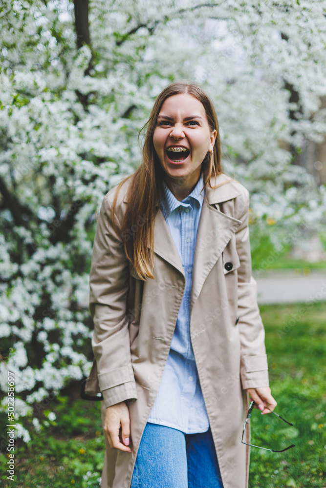 Young attractive smiling woman with a beautiful hairdo on a background of blooming pink apple tree. Selective fokus in woman Young attractive smiling woman with a beautiful hairdo on a background of blooming pink apple tree. Selective fokus in woman