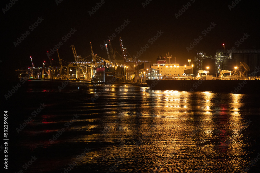 The industrial lighting emitted from The Port of Brisbane operating at night. The industrial lighting emitted from The Port of Brisbane operating at night.