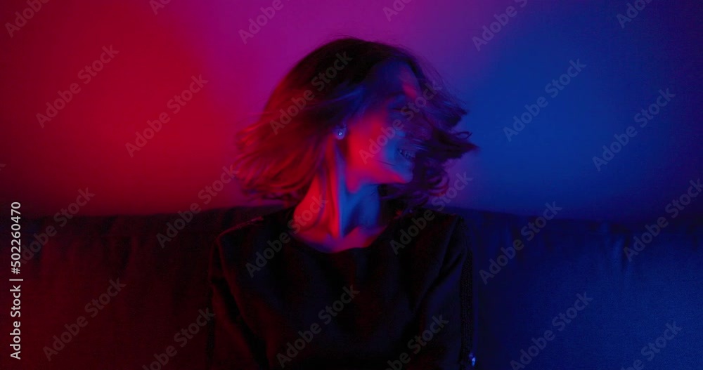 Cheerful teen girl having fun on the multicolored light. She is shaking her head with long hair and smiling. Cheerful teen girl having fun on the multicolored light. She is shaking her head with long hair and smiling.