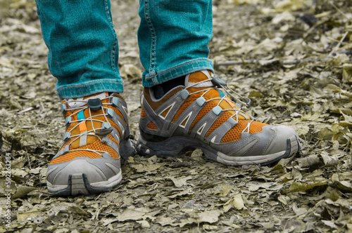 sneakers on the path. man stands with her foot in the woods. illustration of travel. orange shoes on a natural background. hiking concept
