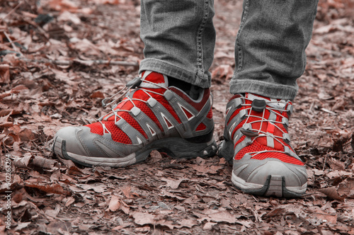 sneakers on the path. man stands with her foot in the woods. illustration of travel. red shoes on a natural background. hiking concept