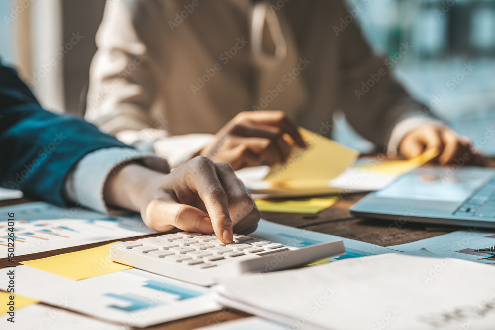 Businessman using a calculator to calculate numbers on a company's financial documents, he is analyzing historical financial data to plan how to grow the company. Financial concept. Businessman using a calculator to calculate numbers on a company's financial documents, he is analyzing historical financial data to plan how to grow the company. Financial concept.