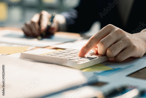 Businessman using a calculator to calculate numbers on a company's financial documents, he is analyzing historical financial data to plan how to grow the company. Financial concept.