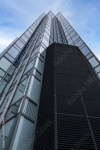 Low angle looking up at tall corporate glass window office buildings