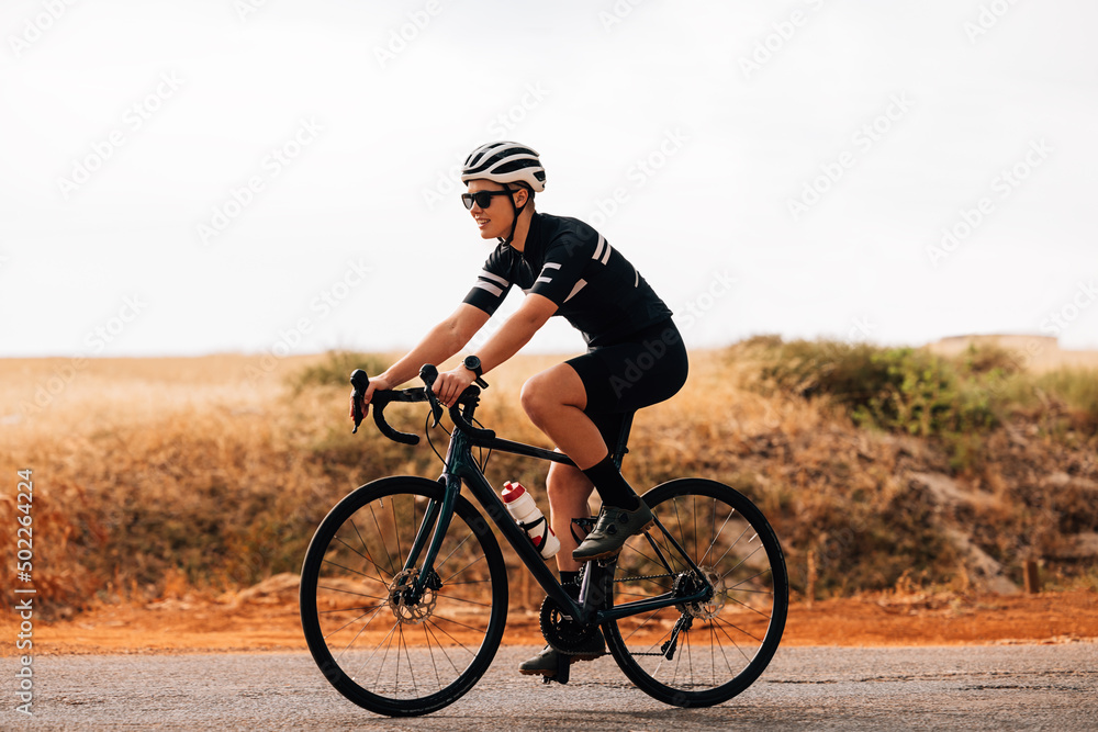 Side view of professional woman cyclist riding her bike outdoors Side view of professional woman cyclist riding her bike outdoors
