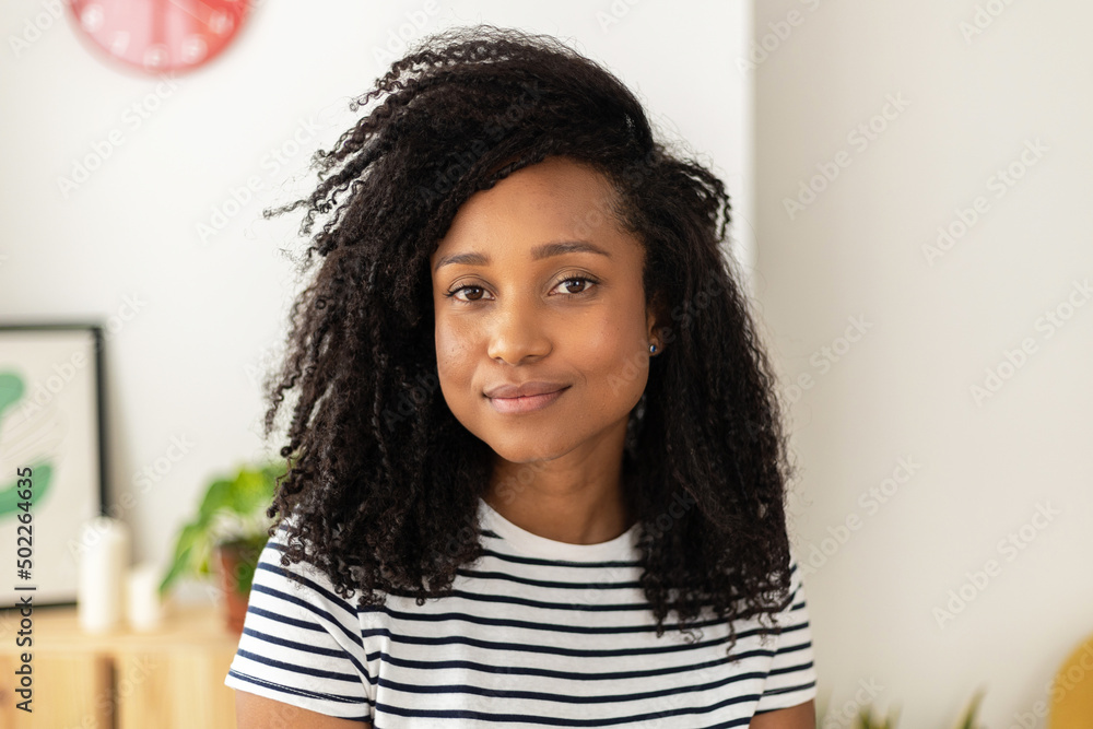 © Xavier Lorenzo - Confident young brazilian woman looking at camera while standing at home - Screen view webcam portrait of african american female