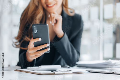 Young businesswoman looking at financial information from a mobile phone, she is checking company financial documents, she is a female executive of a startup company. Concept of financial management.