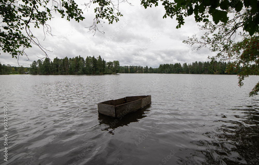 An empty boat is floating on the lake.A homemade boat made of planks sails from the shore of a forest lake.