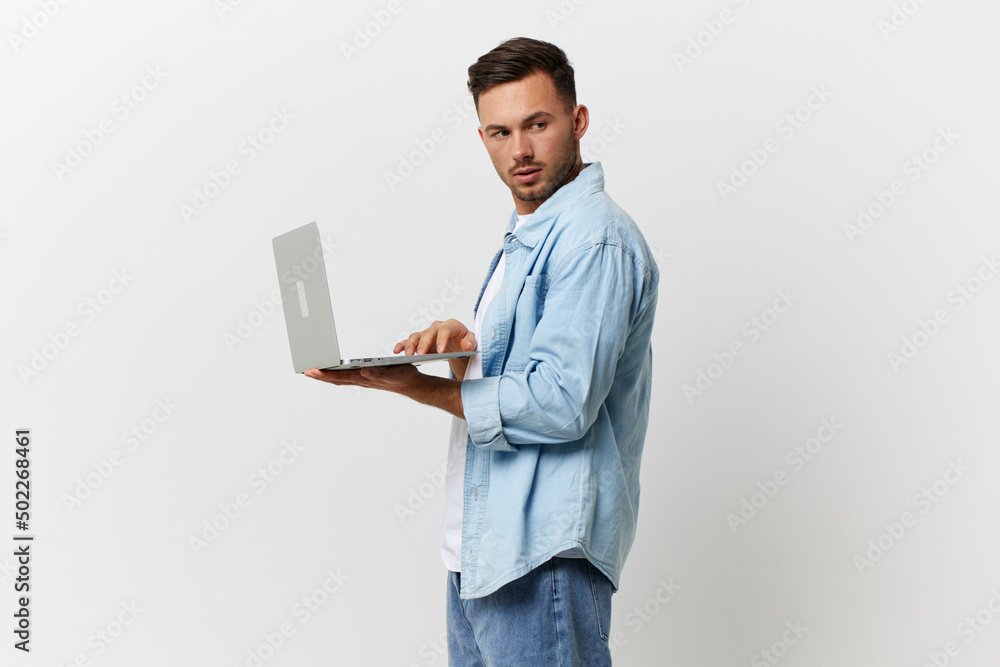Serious cautious handsome man in casual basic t-shirt sends a secret email with laptop look aside posing isolated on white studio background. Copy space Banner Mockup. Electronics repair IT concept Serious cautious handsome man in casual basic t-shirt sends a secret email with laptop look aside posing isolated on white studio background. Copy space Banner Mockup. Electronics repair IT concept